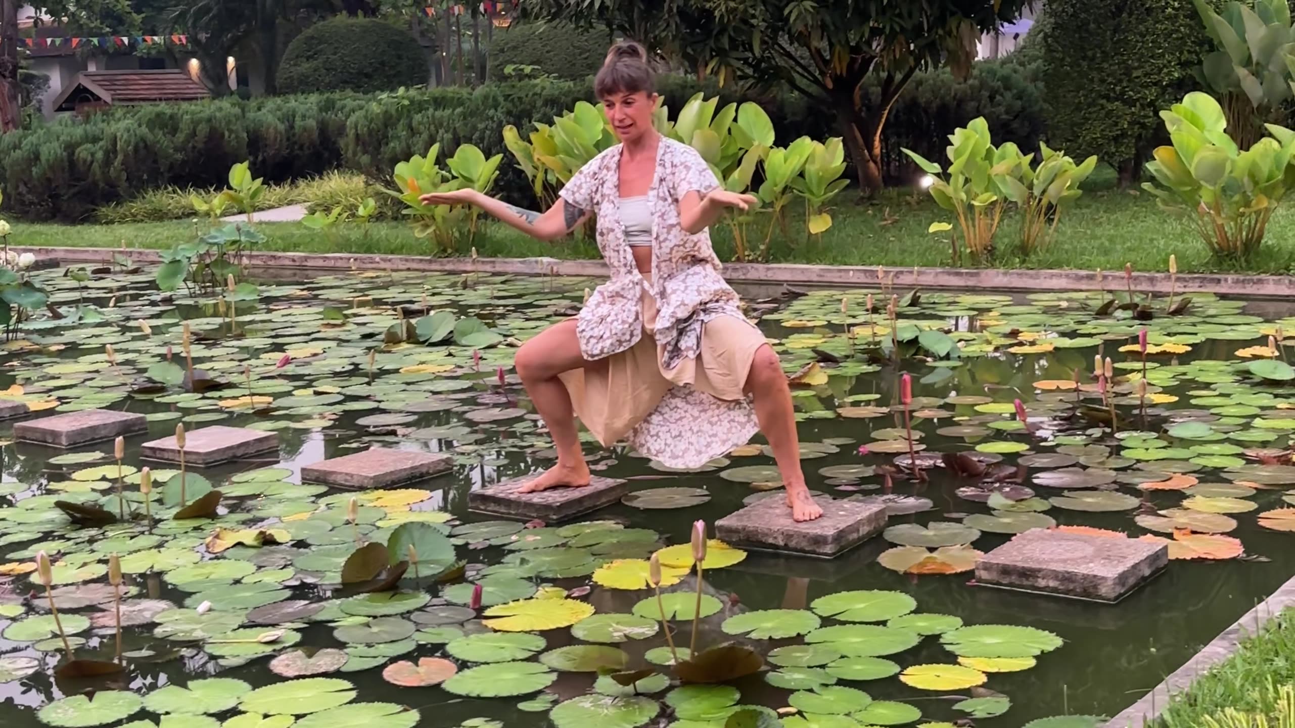 Lola reaching through a wing-like movement in a yellow dress outdoors