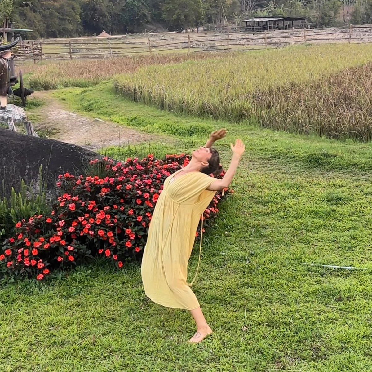 Lola expanding through a lifted spiral movement in a yellow dress outdoors