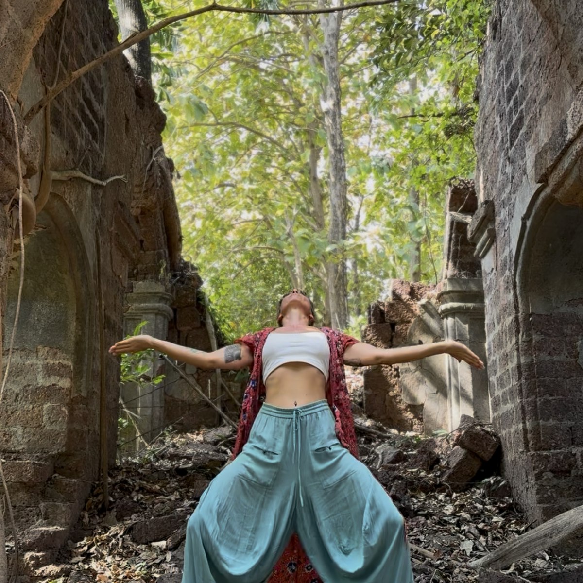 Lola opening the shoulders and chest through Dragon Wings movement under a stone arch