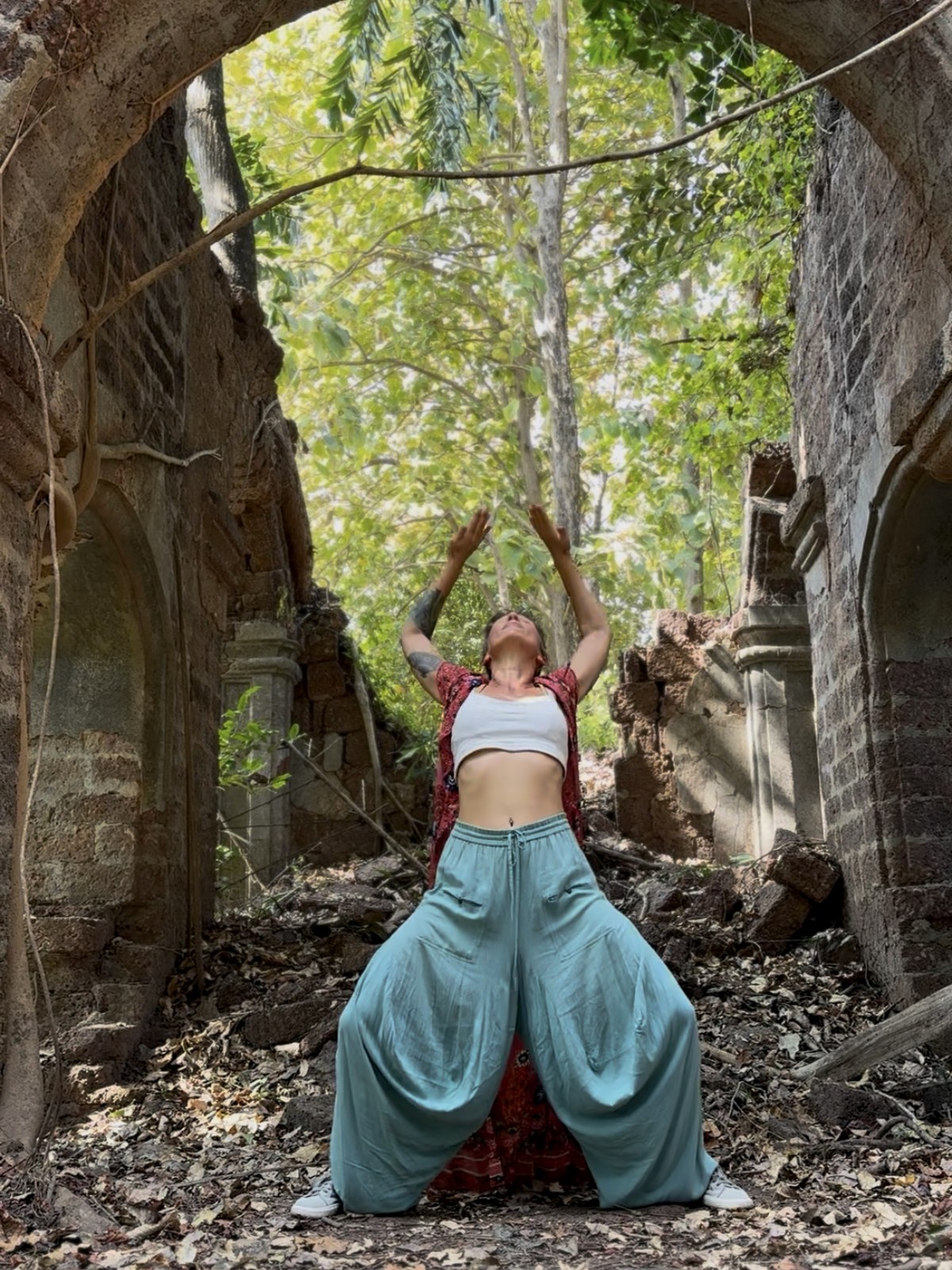 Lola Agni practicing Dragon Wings shoulder and wing movement under a stone arch
